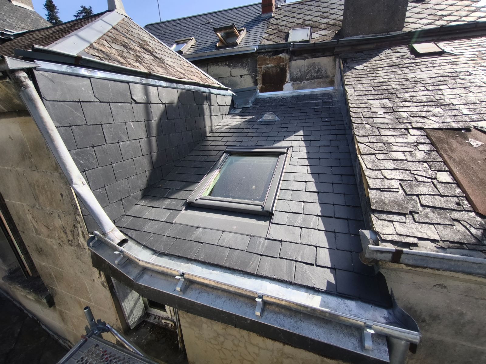 Toiture en ardoise achevée avec fenêtre et gouttière en zinc